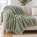 Plaid de canapé en flanelle vert sauge posé sur un canapé en lin beige