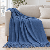 Plaid de canapé léger en maille bleu jean à franges posé sur un canapé en lin beige