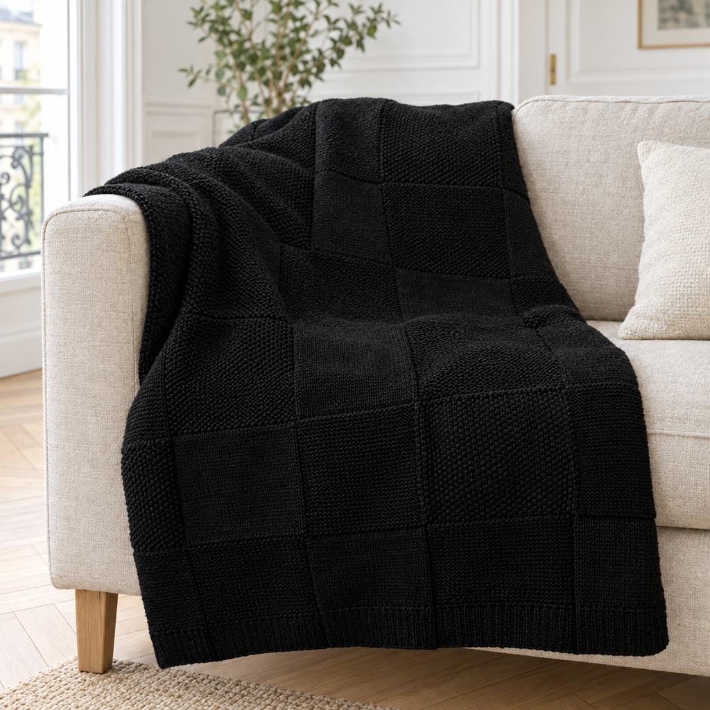 Plaid de canapé en maille à damier ton sur ton noir posé sur un canapé en lin beige