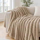 Plaid de canapé à rayures en fausse fourrure taupe posé sur un canapé en lin beige