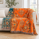 Plaid de canapé en coton jacquard orange et bleu canard à franges posé sur un canapé en lin beige