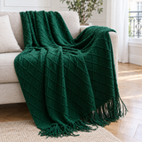 Plaid de canapé mi-saison en maille à losanges vert émeraude à franges posé sur un canapé en lin beige