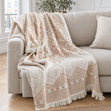 Plaid de canapé en coton jacquard crème et sable à arabesques et franges posé sur un canapé en lin beige