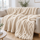Grand plaid de canapé à rayures en fausse fourrure crème posé sur un canapé en lin beige