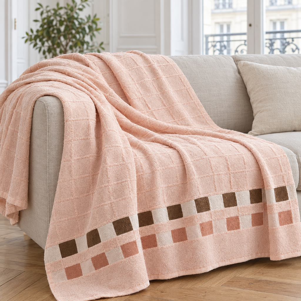 Jeté de canapé en coton éponge pêche à bande de carrés posé sur un canapé en lin beige