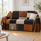 Jeté de canapé en flanelle patchwork noir, rouille et beige recouvrant un canapé